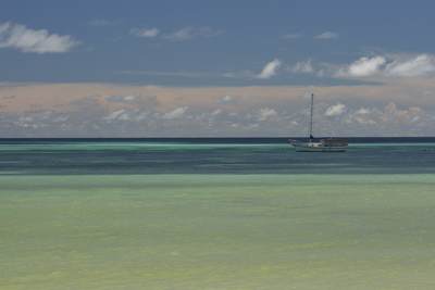 Alone sailing boat moored in the Anse Volbert bay with azure sea and a few clouds in a blue sky on Praline Island in the Seychelles in Africa
