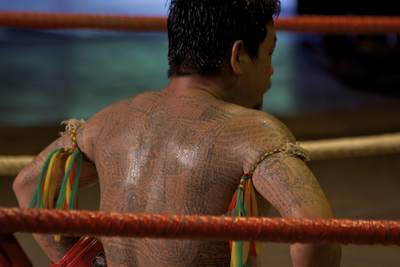 A Thai boxer covered in Thai prayer tattoos, rests in between rounds at the 'Thai Cultural Show' at the Rose Garden Riverside Hotel in Nakhon Pathom in Thailand