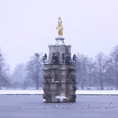The Diana Fountain in Bushy Park near Teddington in the winter with a Mute swan in Middlesex in the United Kingdom
