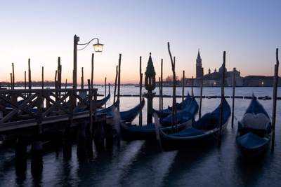 Gondola mooring on San Marco Canal in Venice at dawn with the Church of San Giorgio Maggiore in the distance and lights of the Lido in Italy, Europe