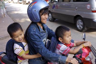 A mother travels with her two sons on a moped on Sakkaline Road in Luang Prabang in Laos