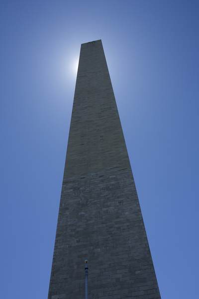 The sun behind the Washington Monument - an obelisk on the National Mall in Washington, D.C., built to commemorate George Washington, the first President of the United States. Located almost due east of the Reflecting Pool and the Lincoln Memorial, made of marble, granite, and bluestone gneiss is both the world's tallest stone structure and the world's tallest obelisk located in the United States of America USA U.S.A.