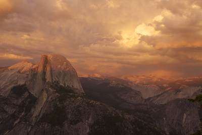 Half Dome and surrounding peaks in the evening light as the sun set with storm clouds gathering, viewed from Glacier Point in Yosemite National Park in California in the United States of America in the USA U.S.A.