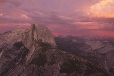 Half Dome and surrounding peaks in the evening light as the sun set with storm clouds gathering, viewed from Glacier Point in Yosemite National Park in California in the United States of America in the USA U.S.A.