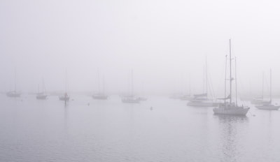 Boats moored in fog in Morro Bay harbour (a commercial harbour for fishing boats) - partially designated as a state and national bird sanctuary and also declared a California Marine Reserve by the California Fish and Game Commission in the United States of America in the USA U.S.A.