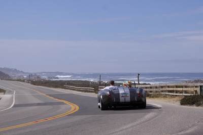 Young couple driving in an open topped sports car along '17-mile Drive' in Monterey peninsula in California in the United States of America USA U.S.A.