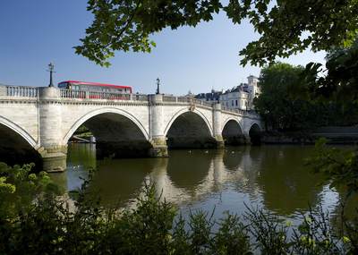 Richmond bridge over the river Thames with a red bus passing over it in the spring morning sunshine in the London Borough of Richmond in the United Kingdom