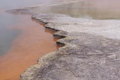 Champagne Pool with steam rising - a hot spring with minerals such as sulphur, arsenic, gold and antimony deposited on the surrounding sinter ledge giving the bright colours near Rotorua on North Island New Zealand
