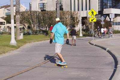 A man skate-boards along the cycle way next to the boardwalk on Santa Monica beach in Los Angeles, California, United States of America USA U.S.A.