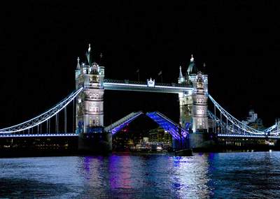 Floodlit Tower bridge over the river Thames opens to allow ships to pass at night in central London in the United Kingdom