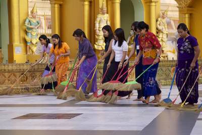 It is considered a good deed to help sweep the Shwedagon Pagoda marble flooring - at around 6pm many people (women and men work separately) sweep the marble floor in a line working in a clockwise direction around the central stupa of the complex in Yangon (Rangoon) in Myanmar (Burma)