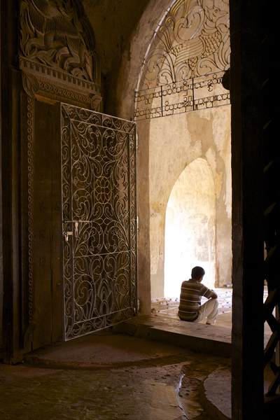 Entrance doorway with carved wooden doors and wrought iron gates leading into the Shwegugyi Temple meaning 'the Golden Cave' (Nandaw Oo Paya) in Bagan in Myanmar (Burma)