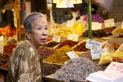 A woman shops at a dried fruit stall at Maeklong Railway Market (Risky market Talad Rom Hub) in Thailand
