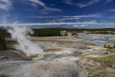 A view of Porcelain Basin from the overlook with steaming geysers, pools coloured milky blue by silica and orange and red colours from minerals such as iron and arsenic, with a walkway for visitors through the middle in Yellowstone National Park in Wyoming in the United States of America USA U.S.A.