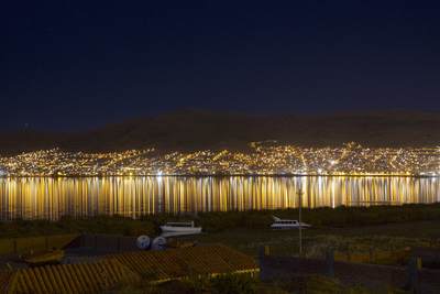 The street lights of Puno reflected in Lake Titicaca at night in Peru in South America
